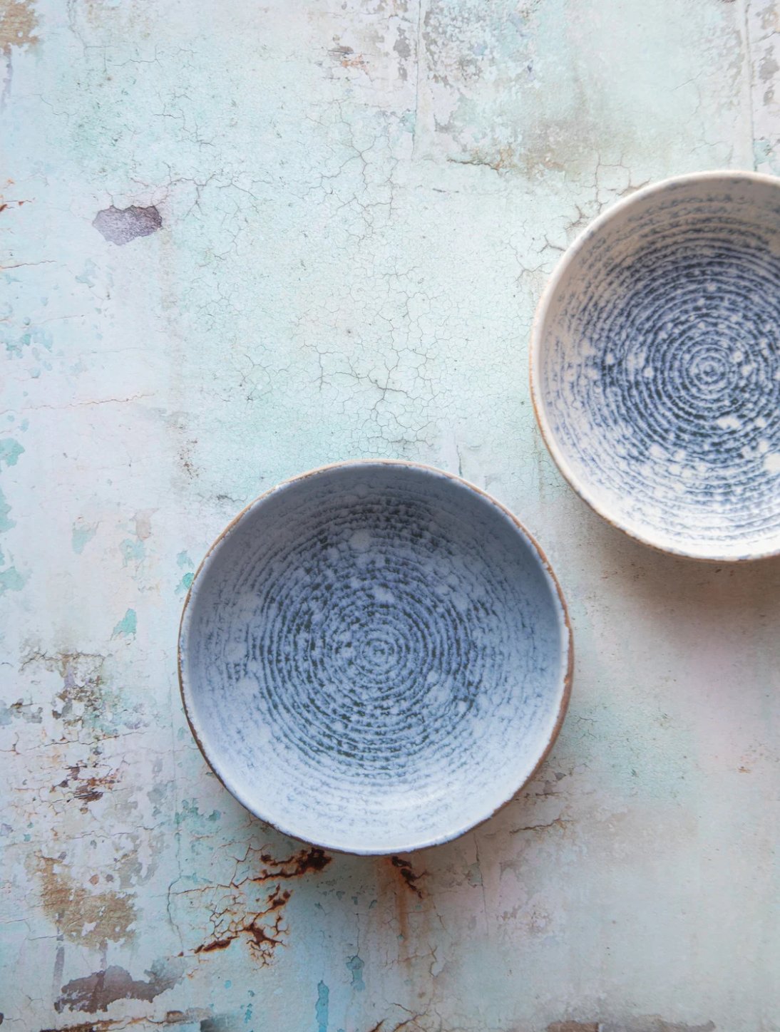 Two glazed bowls on a weathered surface, viewed from above