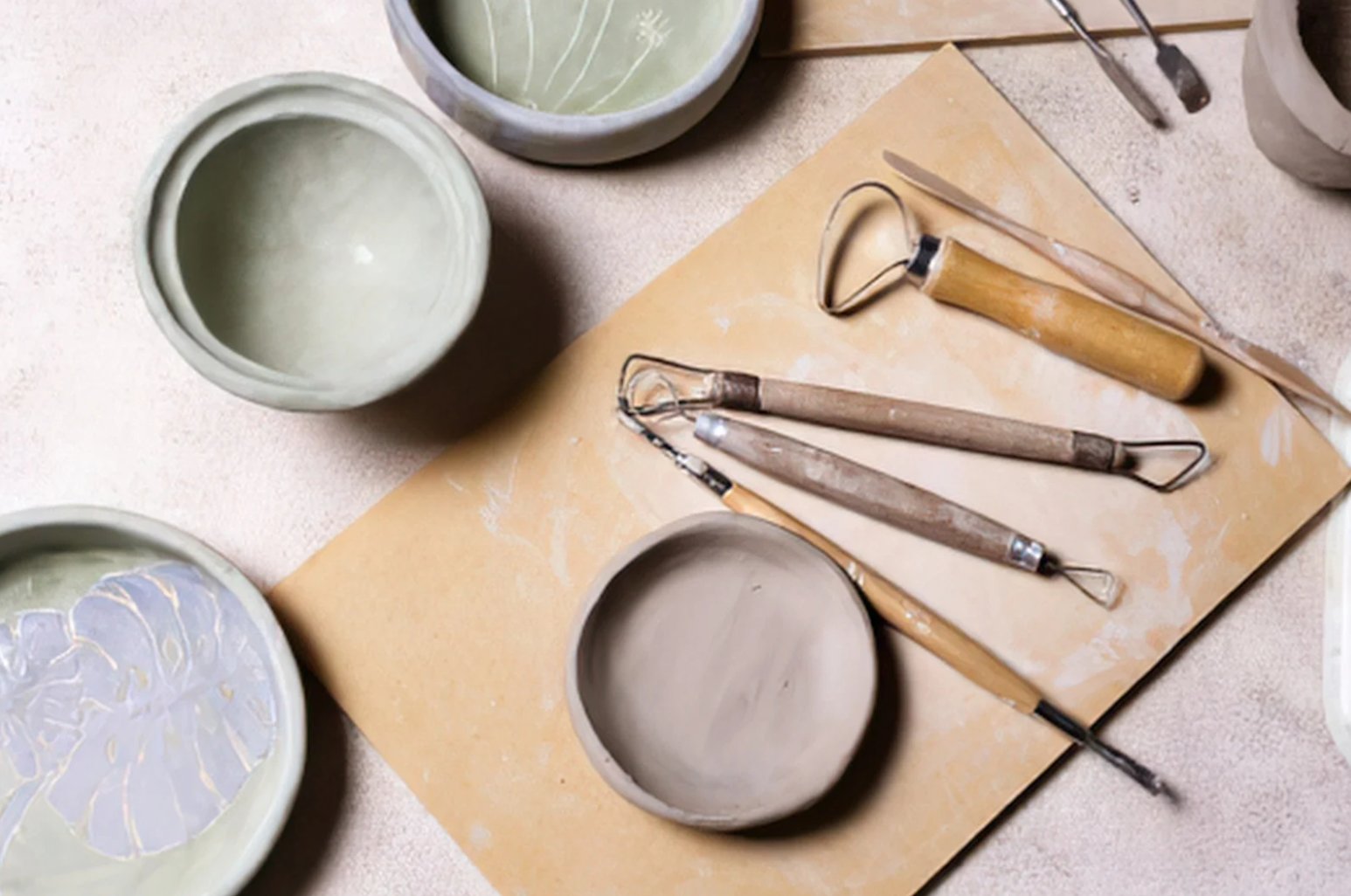 A top-down view of bowls and pottery tools on a workbench