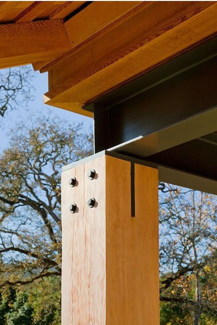 A close-up of a timber post meeting a steel beam with bolts