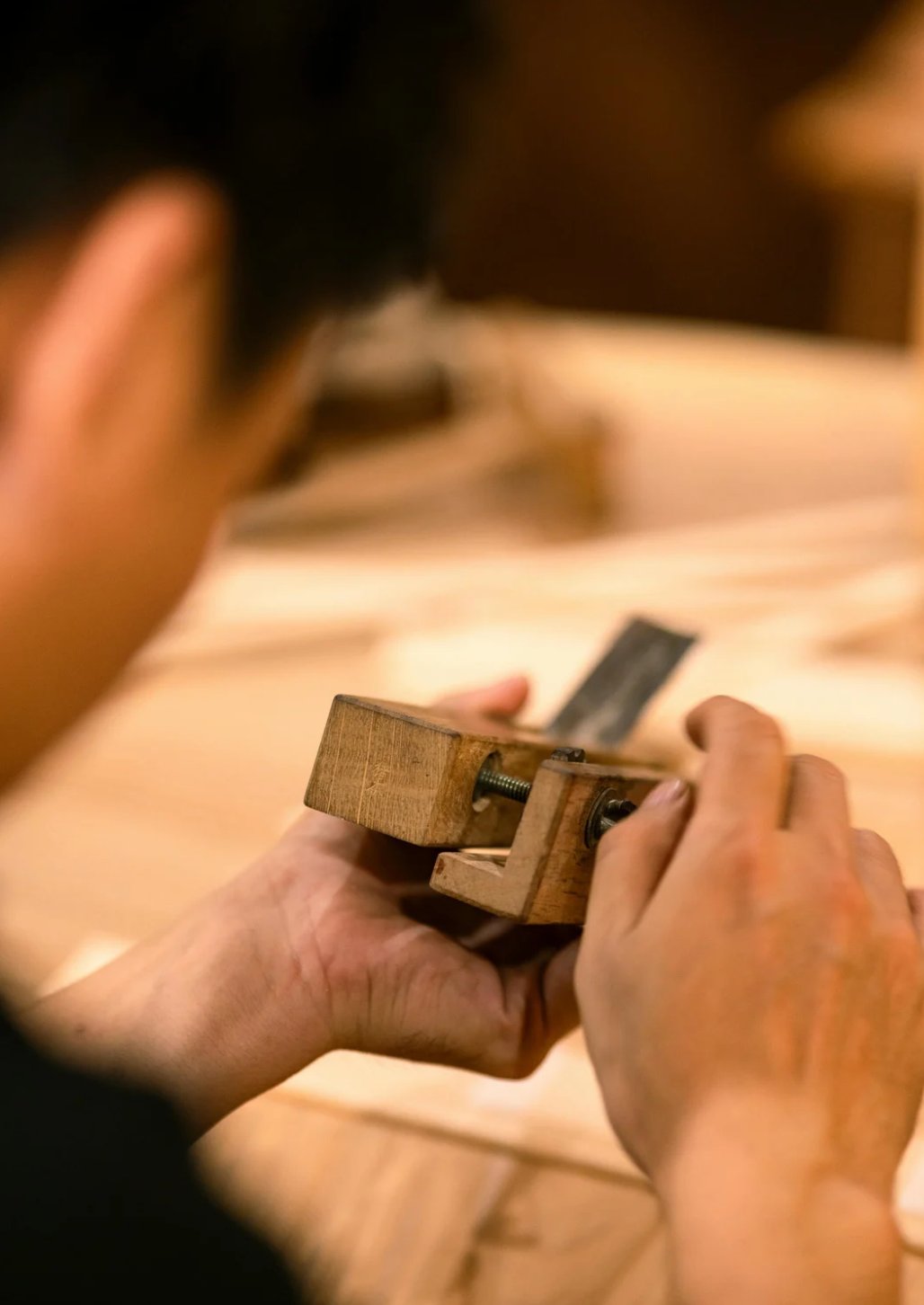 A pair of hands setting the blade of a Japanese plane
