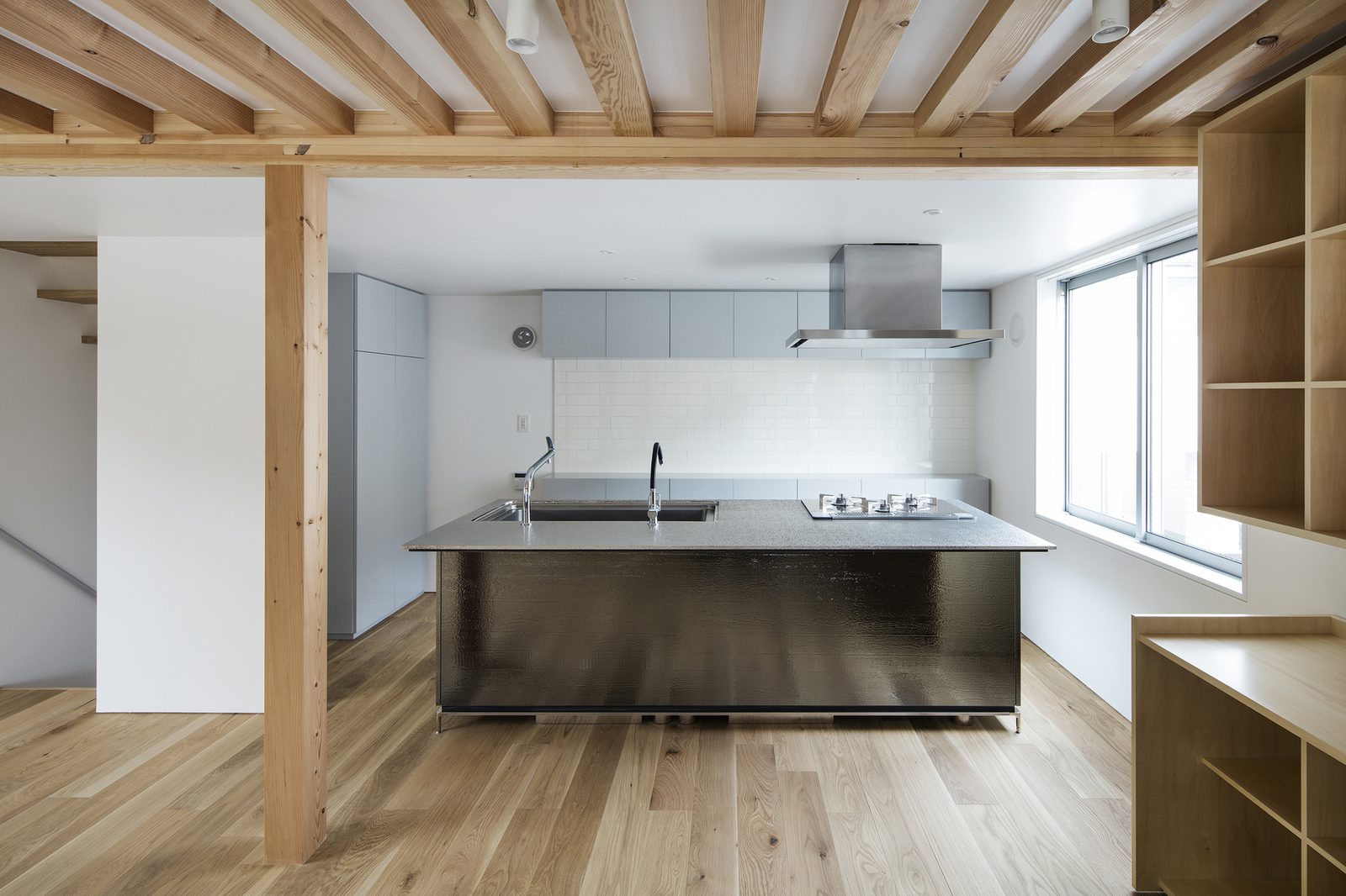 A working kitchen with a steel-clad island under exposed timber beams